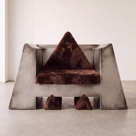 Front view of the Totem armchair by Diamant Versatile, combining a monumental brushed metal shell with dark brown fur upholstery.