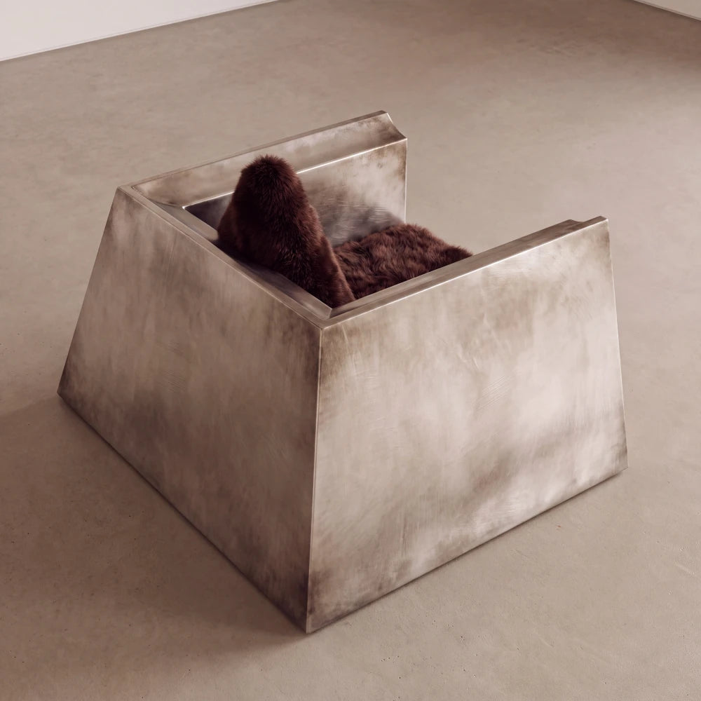 Rear three-quarter view of the Totem armchair by Diamant Versatile, revealing its trapezoidal metal body and triangular fur backrest.