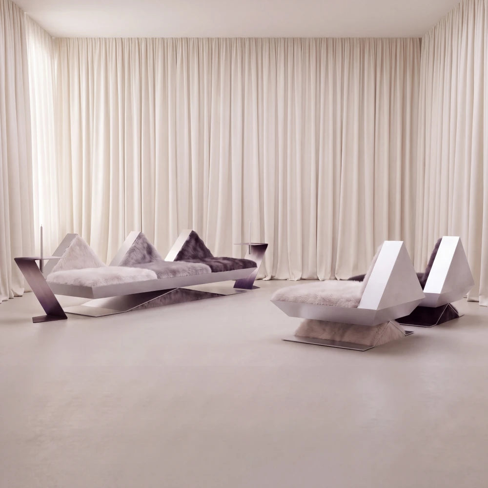 Vertice sofa by Diamant Versatile displayed with matching armchairs in a softly lit interior, featuring angular metal frames and tonal fur upholstery.