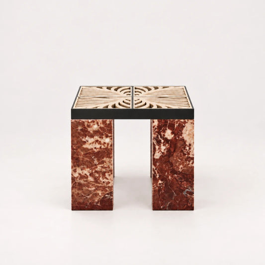 Front view of the Hikari Side Table by Eva Szumilas, showing its beige stone lattice top above richly veined red marble legs.