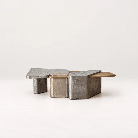 Side view of the Scorpio 150 Coffee Table by Eva Szumilas, showing staggered metallic blocks, overlapping silver-toned tops and a gold-toned extension at one end.