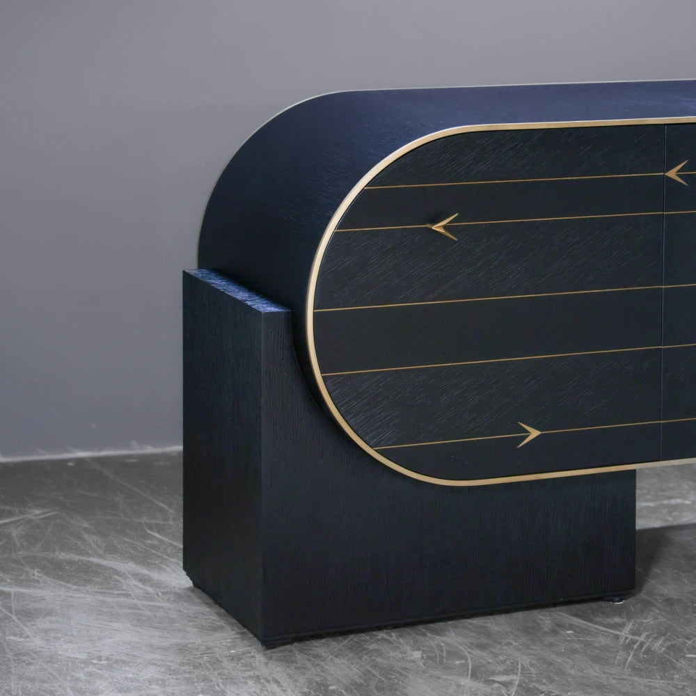 Close-up of the C01 Sideboard by Eva Szumilas, showing its curved dark wooden case, gold-toned edging and rectangular support beneath the rounded door.