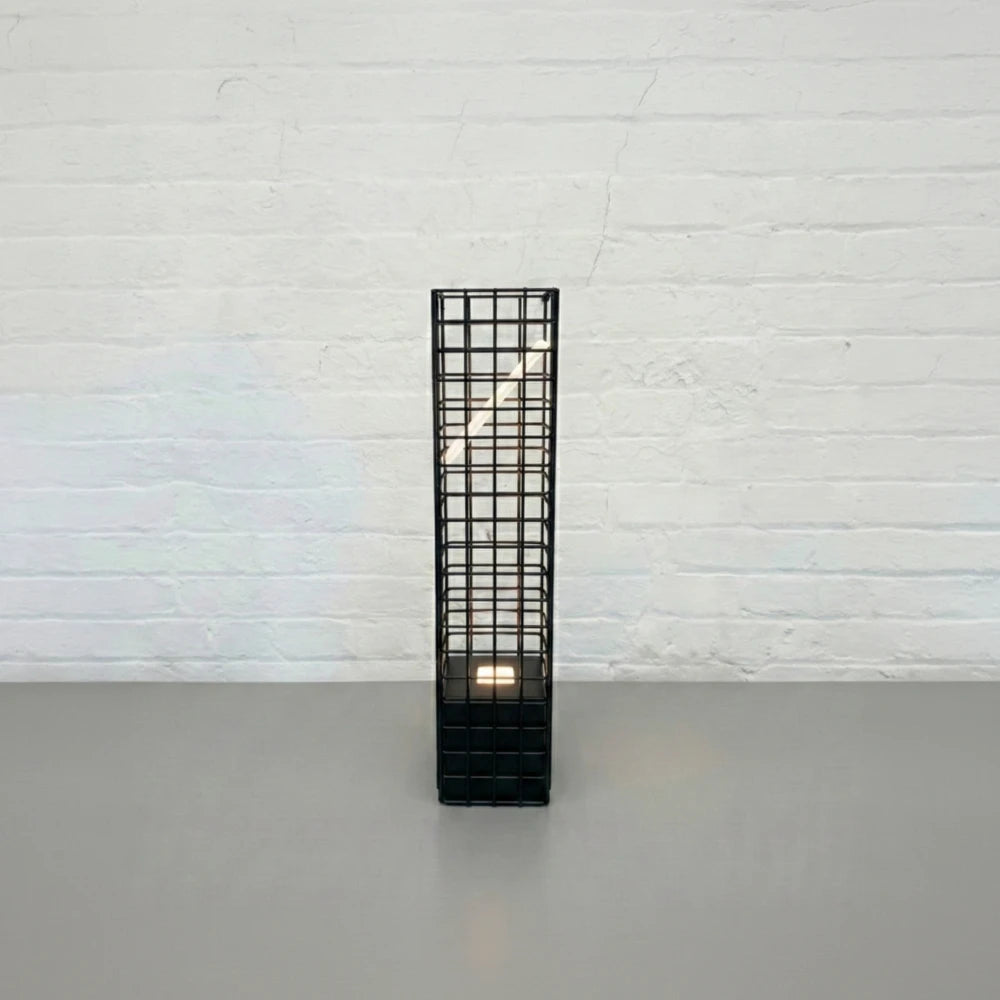 Front view of the black Ami Desk Lamp by Garnier Pingree, with a tall metal grid frame enclosing an angled illuminated panel.