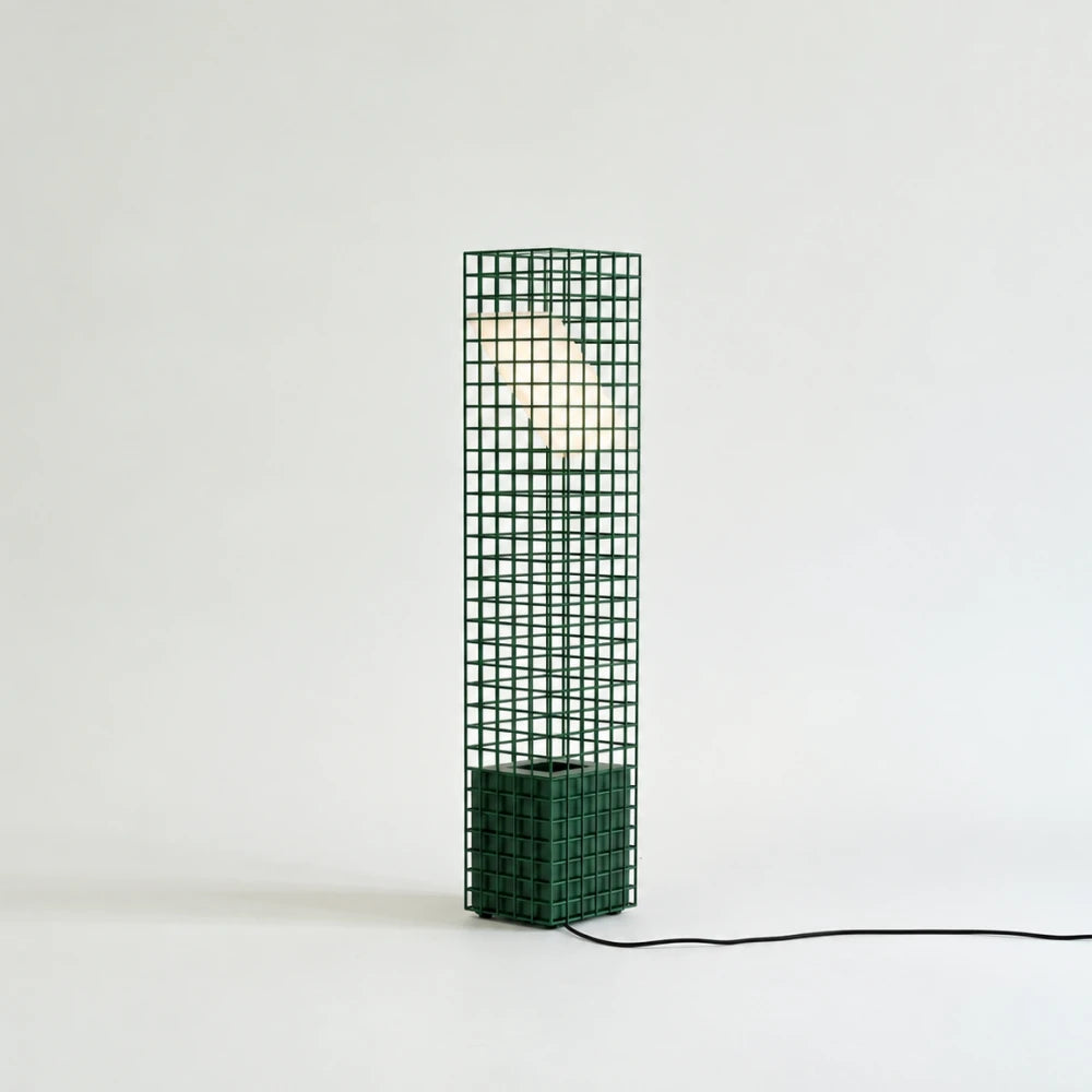 Green Ami Table Lamp by Garnier Pingree with an illuminated angled panel, matching square base and black cable extending across a pale surface.