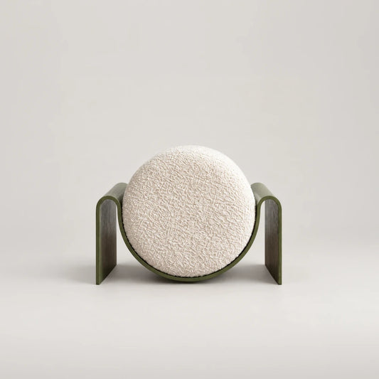Front view of the Monitor Stool by Garnier Pingree, featuring a circular cream bouclé cushion cradled in a green frame with broad side supports.