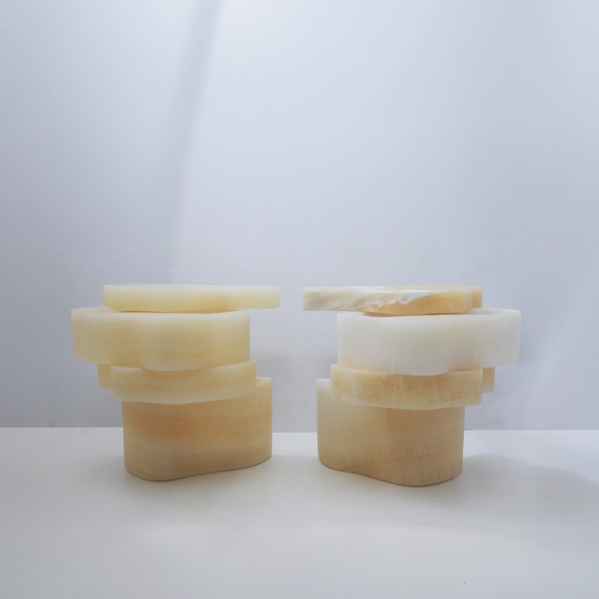 Two open White Moth Nightstands by Panorammma with their rotating onyx compartments arranged differently