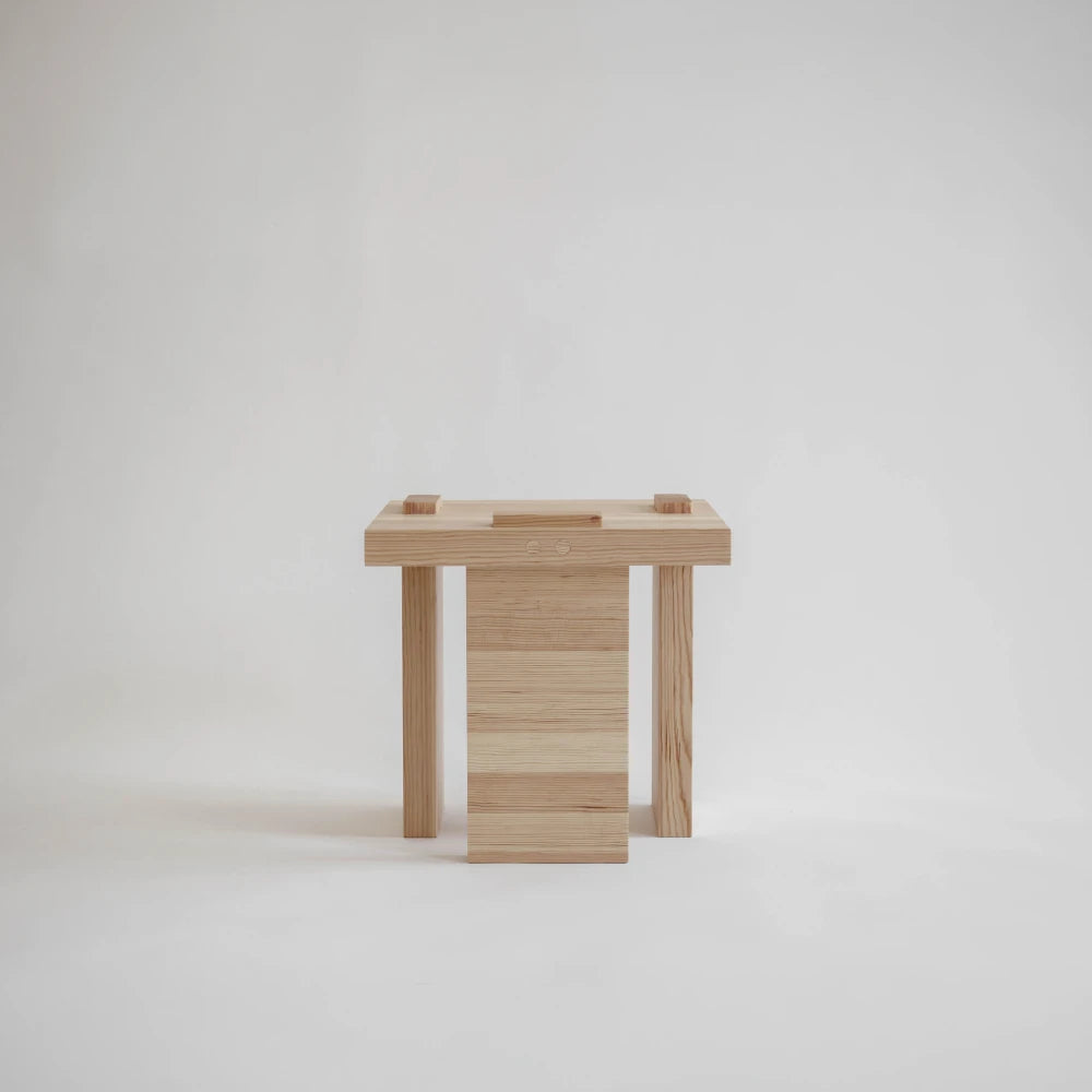 Side view of the Itooraba Stool by Sizar Alexis, highlighting its asymmetric solid pine supports and visible wooden joinery.