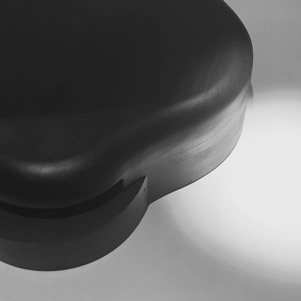 Detailed view of the Lahmu Coffee Table by Sizar Alexis, highlighting its curved black tabletop, layered base, and sculpted junction.