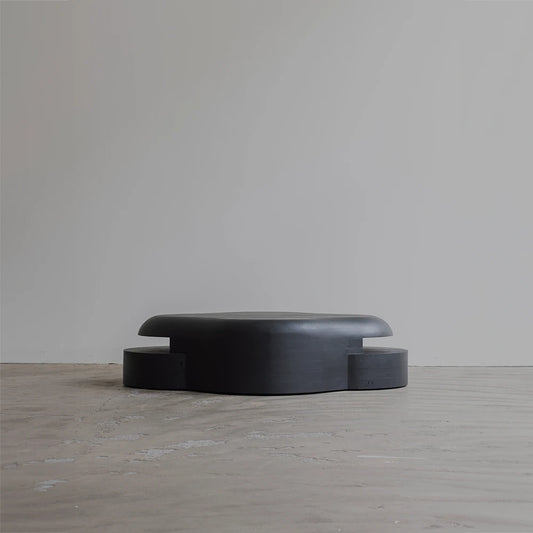 Rear view of the Lahmu Coffee Table by Sizar Alexis, revealing its extended rounded tabletop and symmetrically projecting lower sections.
