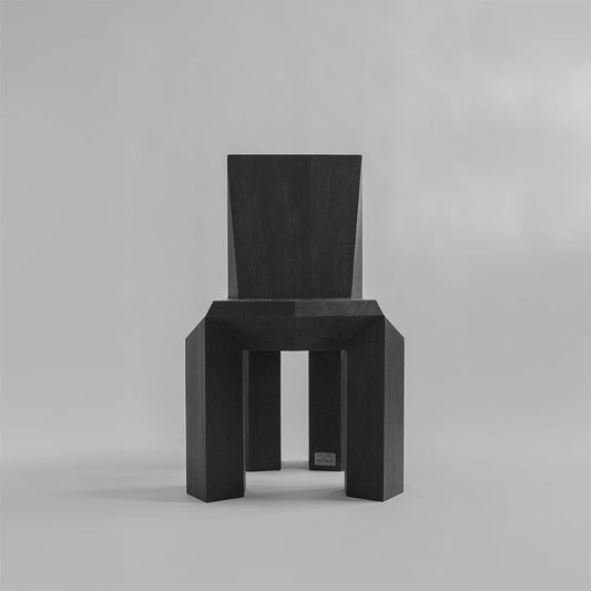 Front view of the black Ode Chair by Sizar Alexis, with a geometric seat, tapered backrest, and four substantial wooden legs.