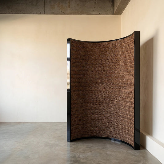 Interior view of The Veil Room Screen by Studio Romell, revealing a curved panel entirely handwoven in textured brown raffia.