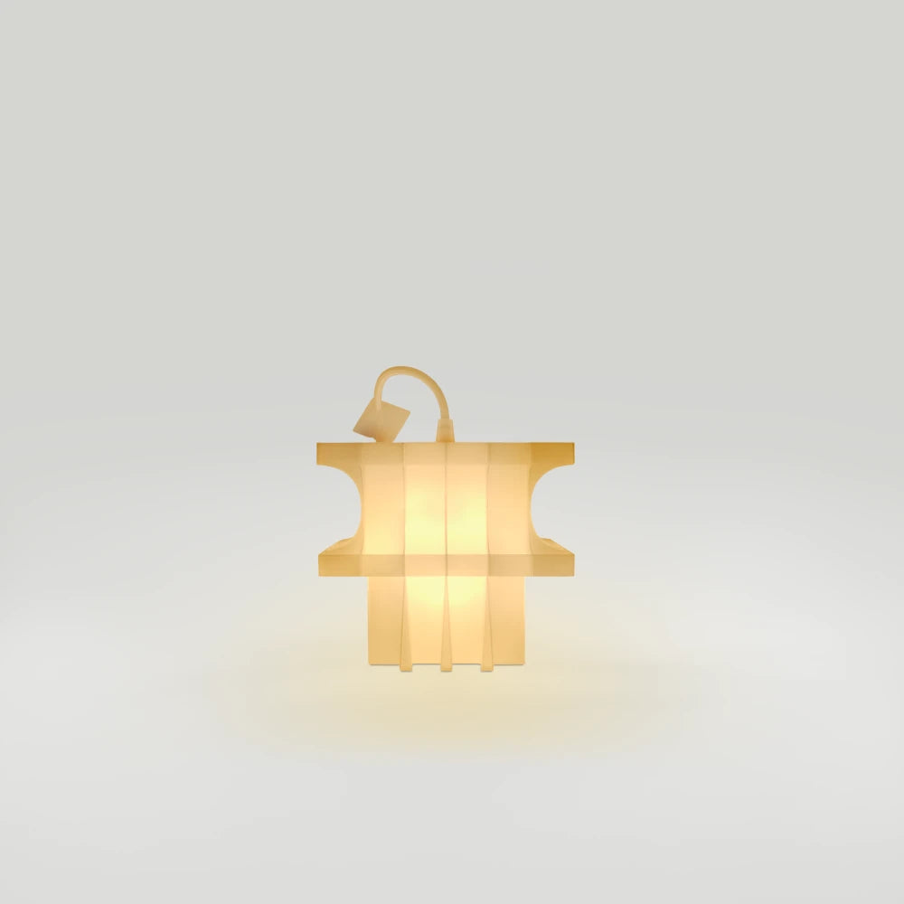Vue de profil de la lampe Citadel Small Lantern allumée, par Ultramar Studio, montrant son profil en retrait, ses panneaux verticaux et son câble en boucle au-dessus du sommet.
