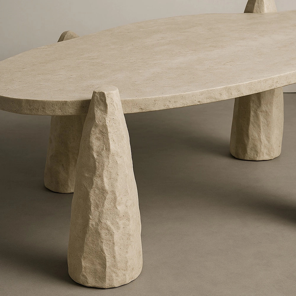 Close-up of a sculpted leg rising through the rough-edged travertine top of the Arx Dining Table by Andres Monnier