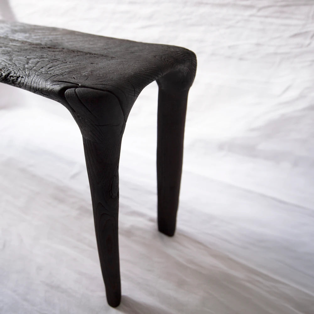 Detail of the Eclipse console by Antoine Maurice, showing its carved oak legs extending continuously from the textured top
