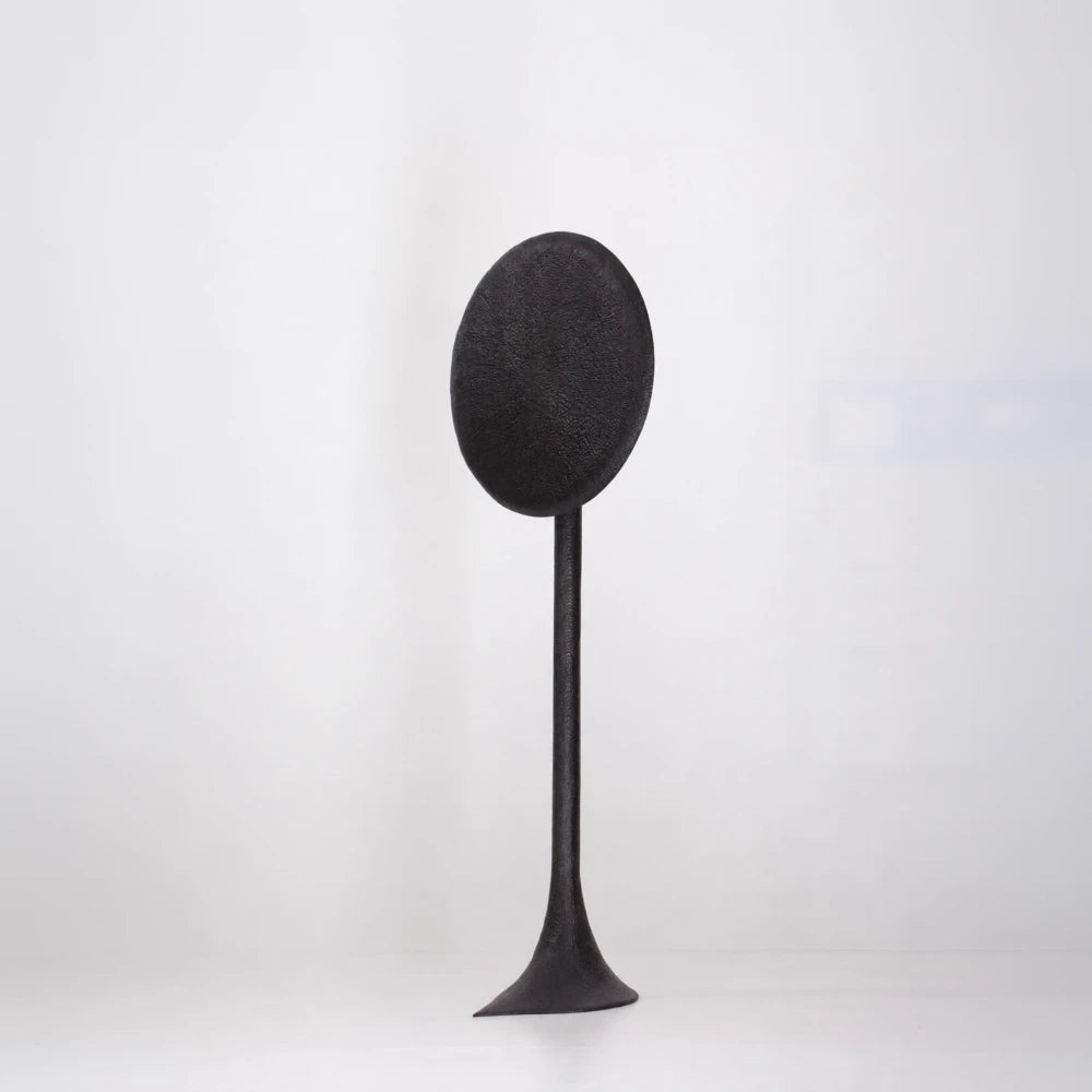 Three-quarter front view of the Solis floor lamp by Antoine Maurice, showing its textured oval disc and flared base