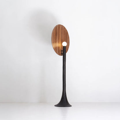 Rear three-quarter view of the illuminated Solis floor lamp, with a glowing sphere set against the walnut disc