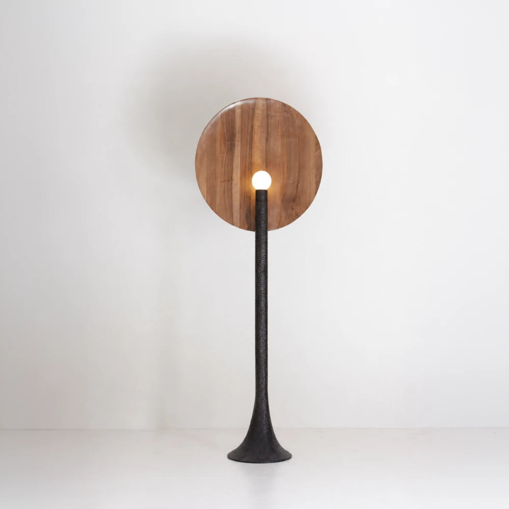 Rear view of the illuminated Solis floor lamp, showing its natural walnut disc and spherical light casting a halo