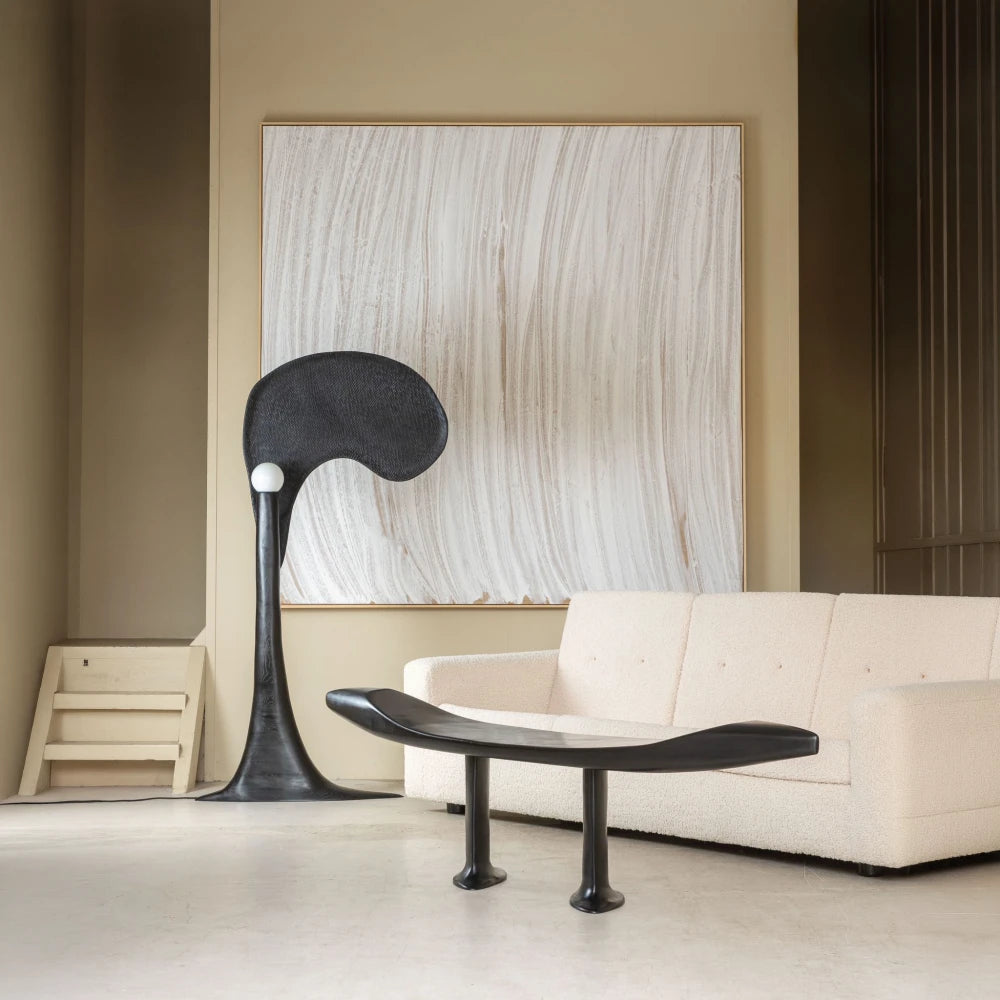 Orphée bench in black carved beech by Antoine Maurice displayed in a contemporary interior beside a cream sofa