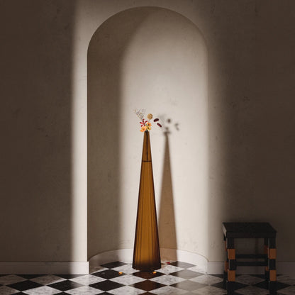 Tall amber Alta Vase by Antony Gasnier with a floral arrangement, displayed beneath an architectural arch