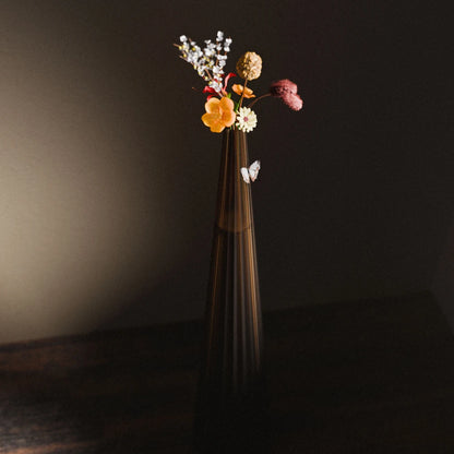 Amber Alta Vase by Antony Gasnier with colourful flowers and a decorative butterfly against a dark background