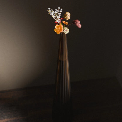 Front view of the tall amber Alta Vase by Antony Gasnier with a colourful floral arrangement