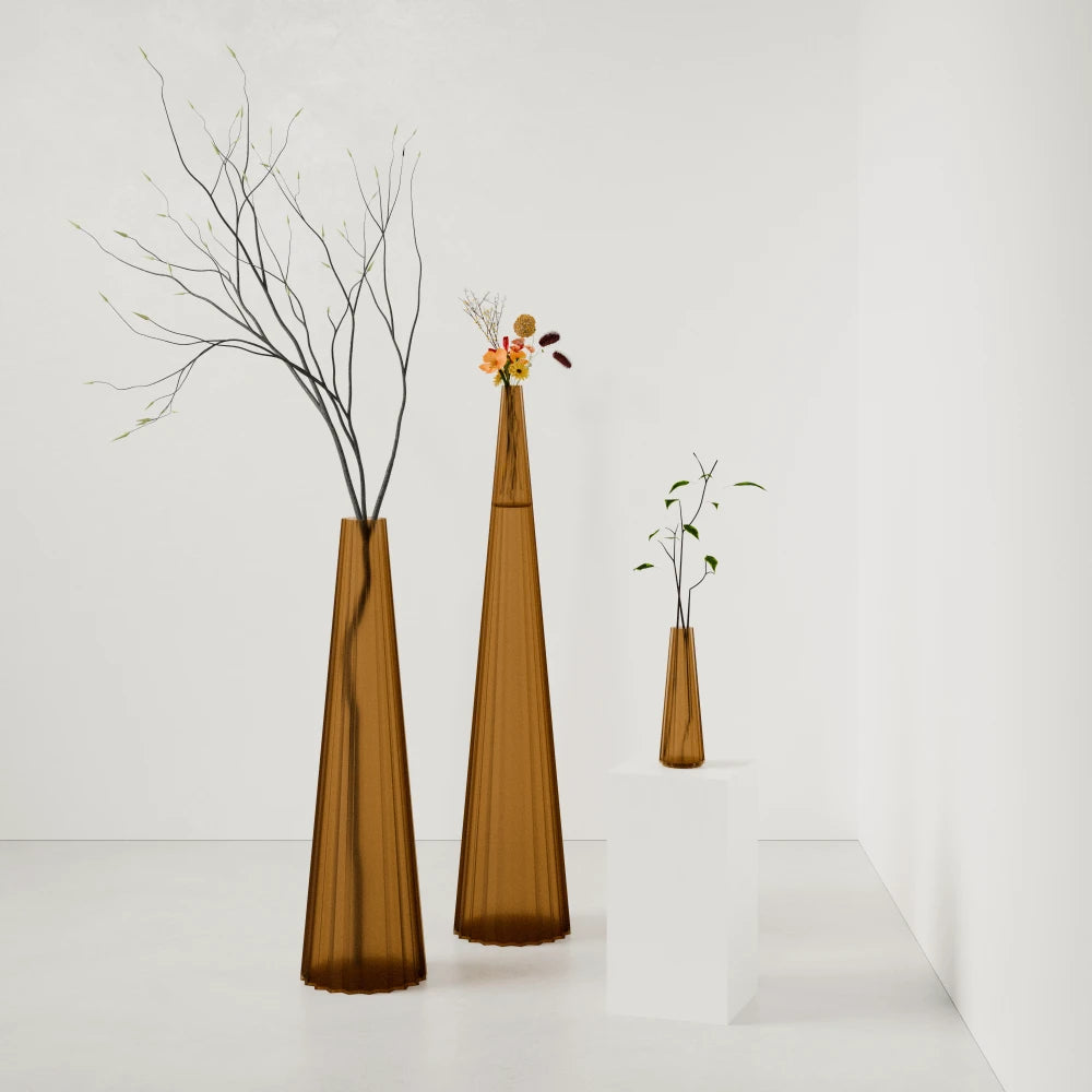 Three sculptural Alta Vases in amber by Antony Gasnier, shown at varying heights with flowers and branches