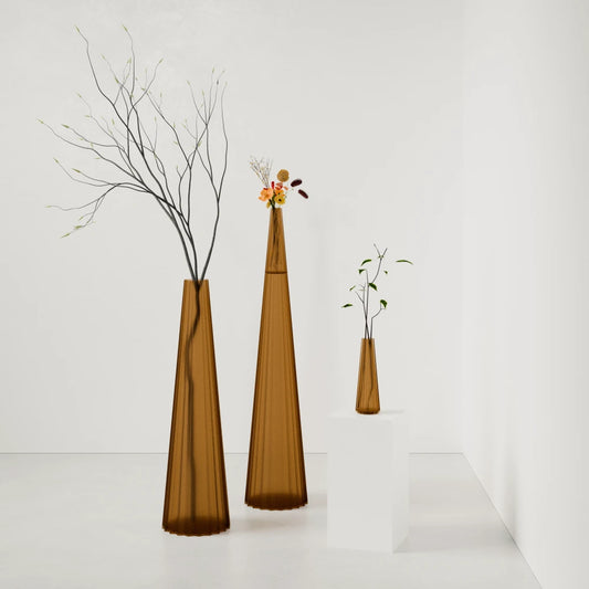 Three sculptural Alta Vases in amber by Antony Gasnier, shown at varying heights with flowers and branches