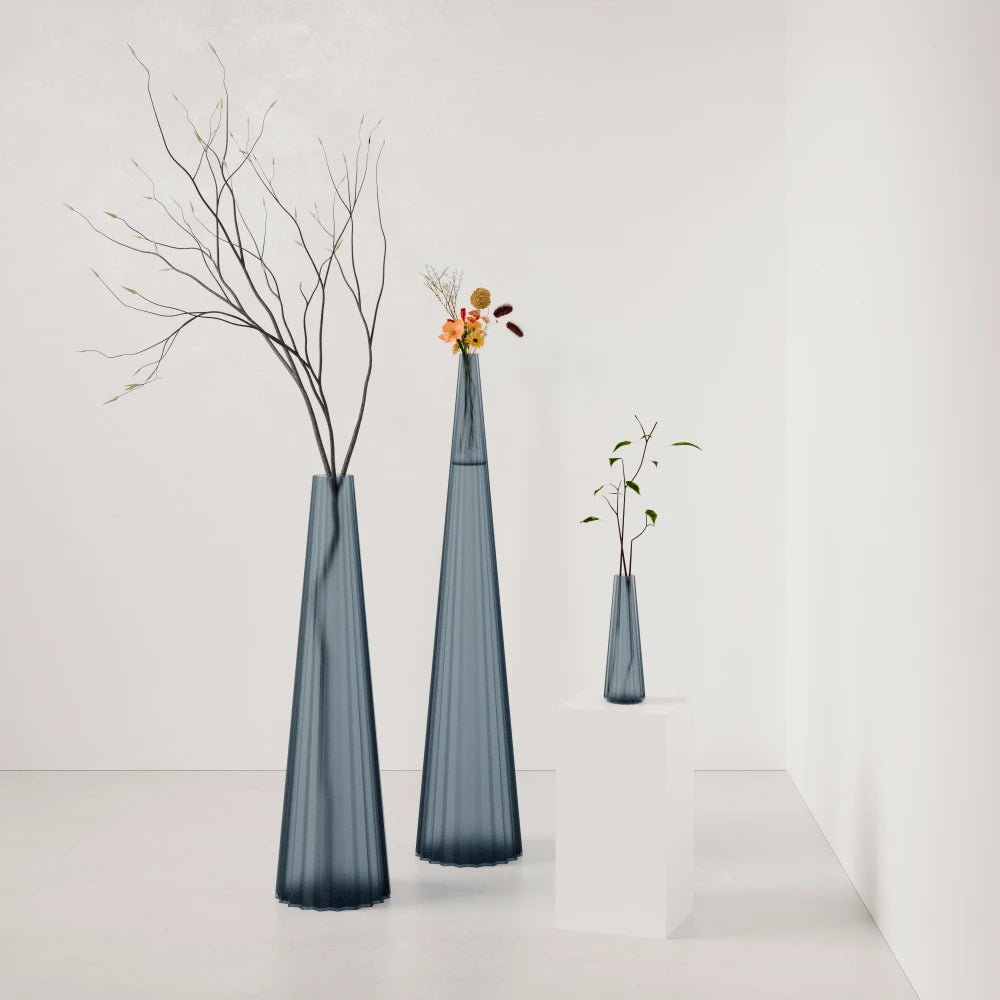 Three fluted Alta Vases in blue-grey by Antony Gasnier, displayed at varying heights with botanical arrangements