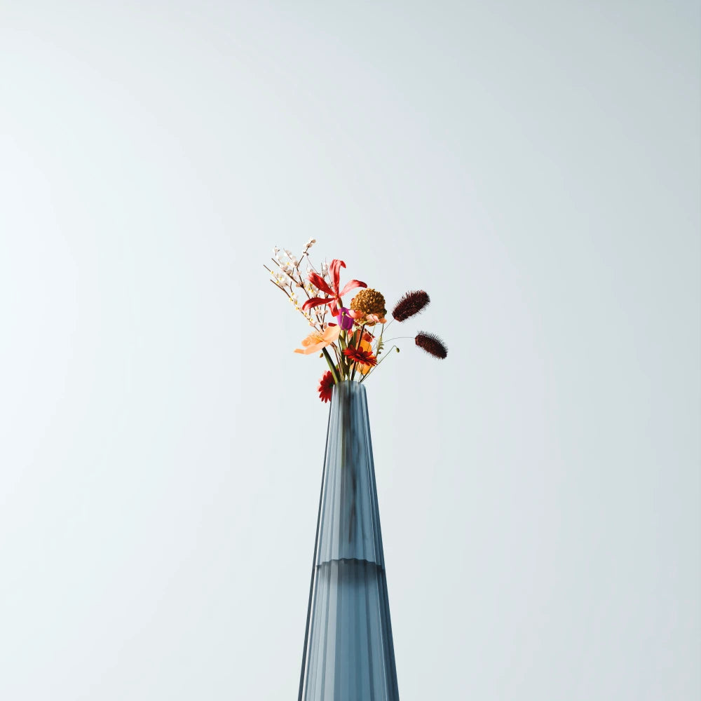 Close-up of a tall blue-grey Alta Vase by Antony Gasnier with a colourful floral arrangement