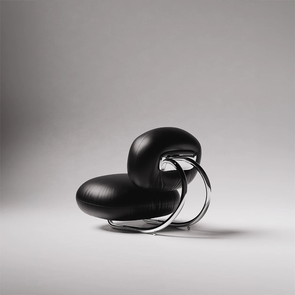Rear three-quarter view of the C8 Armchair by Antony Gasnier, highlighting its curved chrome frame and rounded leather cushions