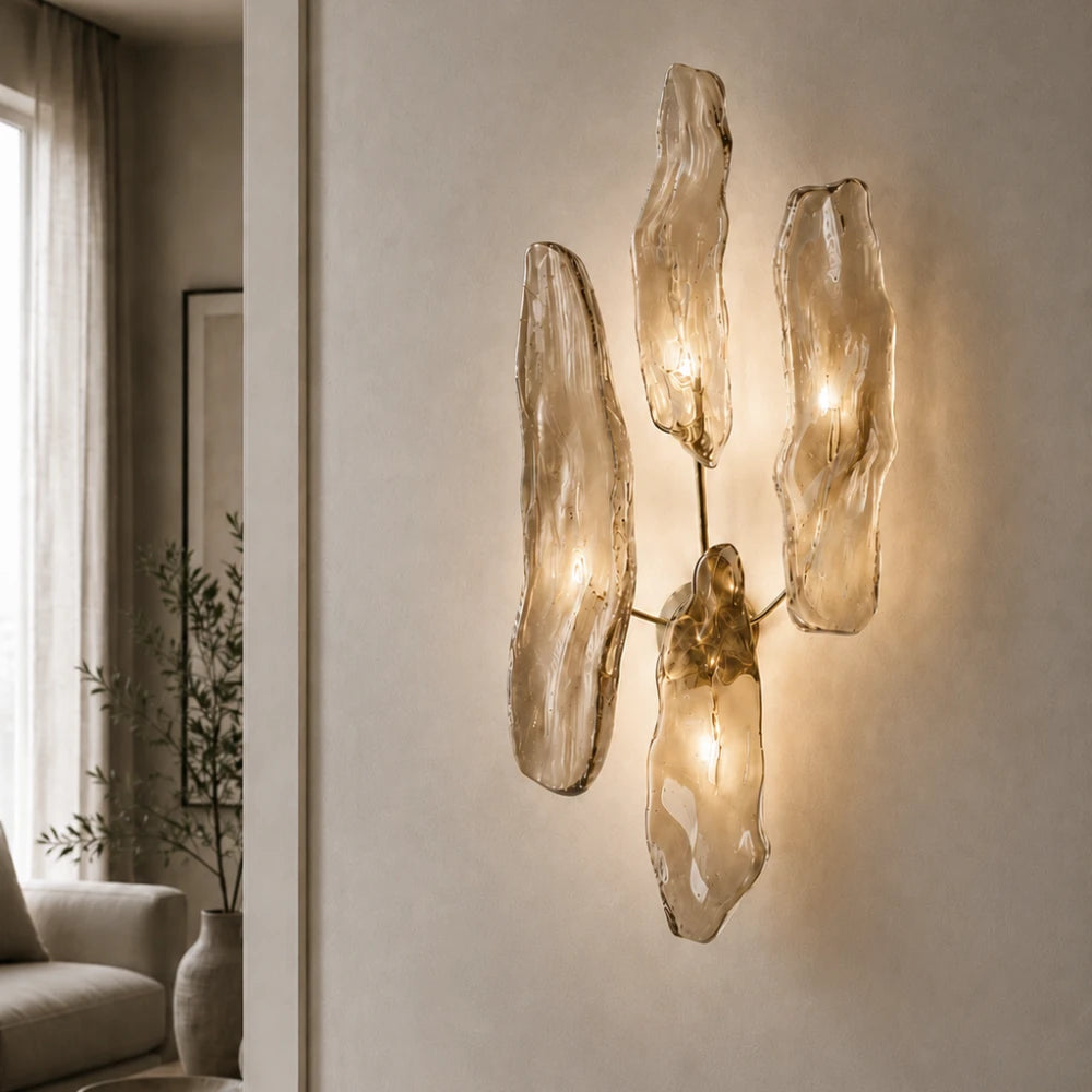 Illuminated Pinaster four-source wall lamp by Antony Gasnier, featuring sculptural amber glass diffusers in a refined living room interior.