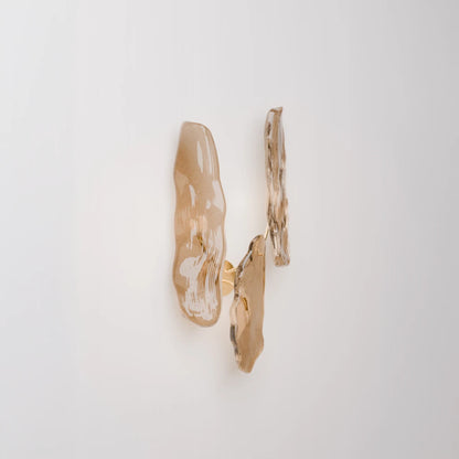 Angled view of the Pinaster three-source wall lamp by Antony Gasnier, softly illuminated through sculptural amber glass diffusers.