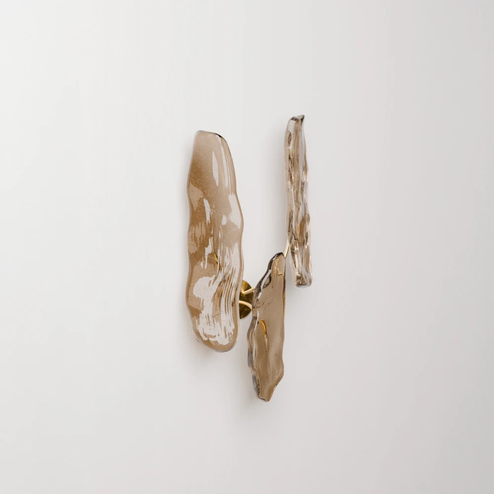 Three-quarter view of Antony Gasnier’s Pinaster wall lamp, showing its layered glass forms and discreet brass mounting.