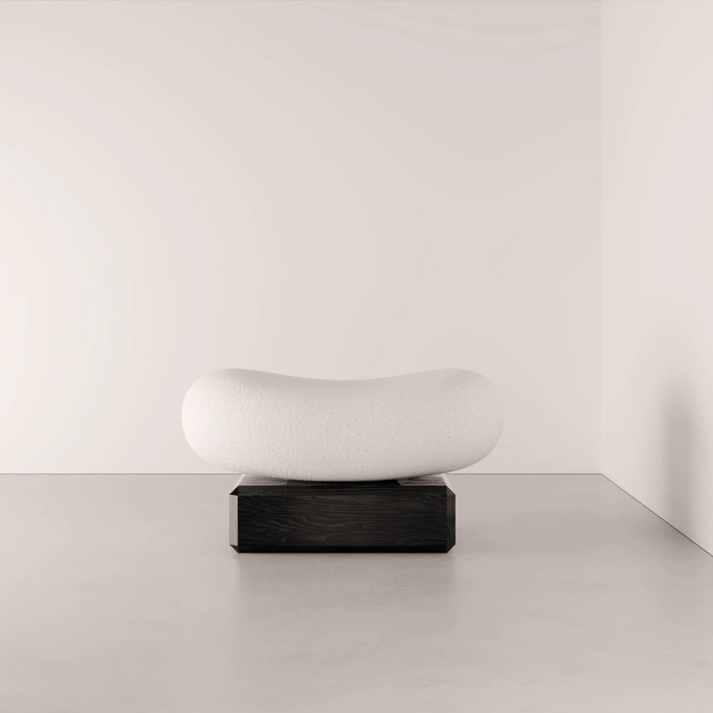 Angled view of the Winter Ottoman by Antony Gasnier, showing its softly hollowed white seat and solid oak base