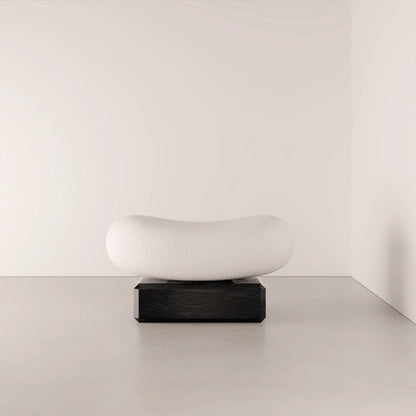 Angled view of the Winter Ottoman by Antony Gasnier, showing its softly hollowed white seat and solid oak base