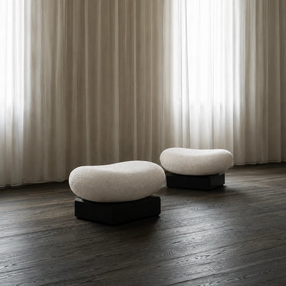 Pair of Winter Ottomans by Antony Gasnier displayed on a dark wood floor beside sheer curtains