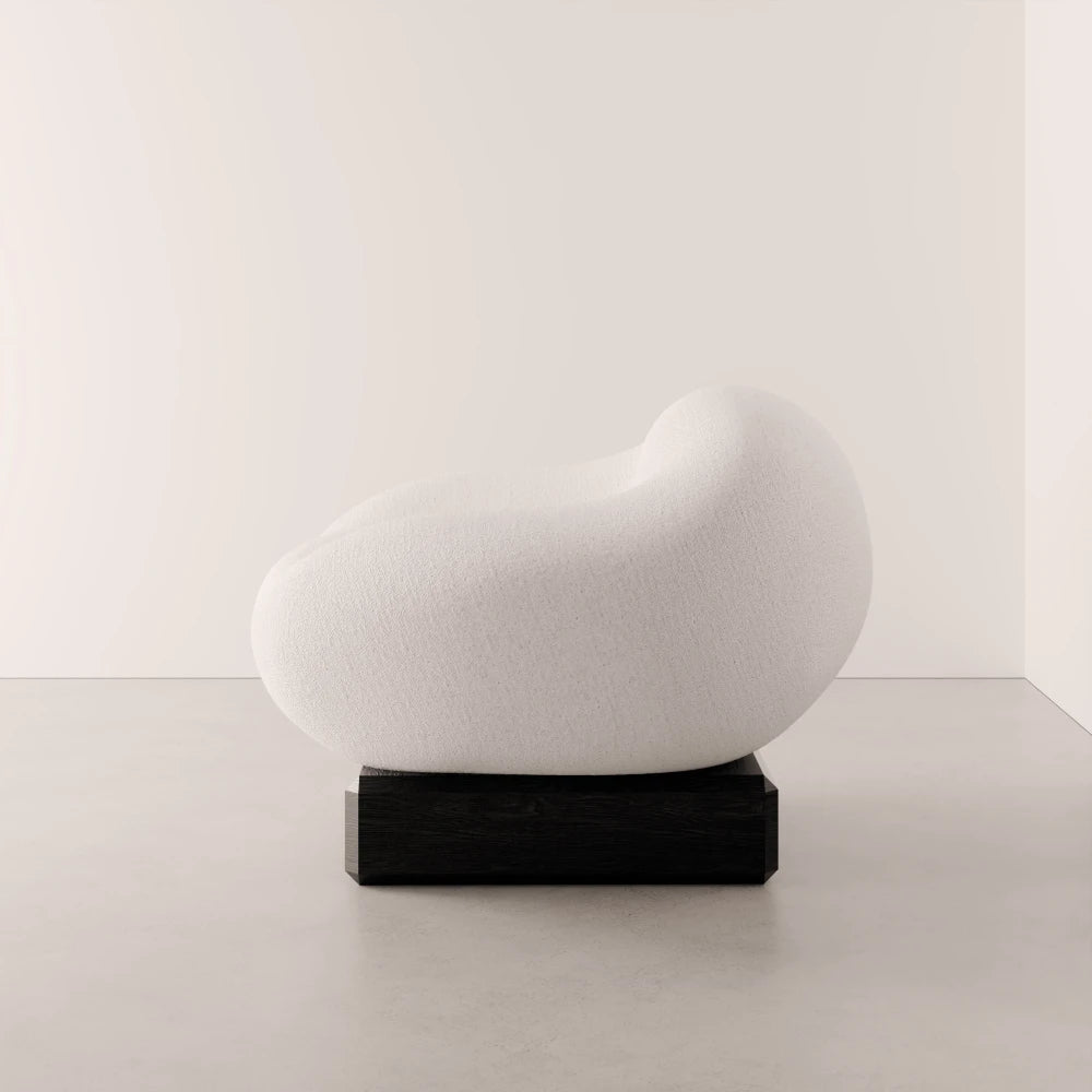 Side view of the Winter Powder Chair by Antony Gasnier, highlighting its continuous upholstered curves and dark oak base