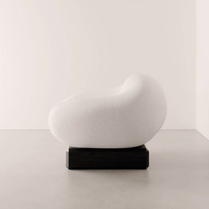 Side view of the Winter Powder Chair by Antony Gasnier, highlighting its continuous upholstered curves and dark oak base