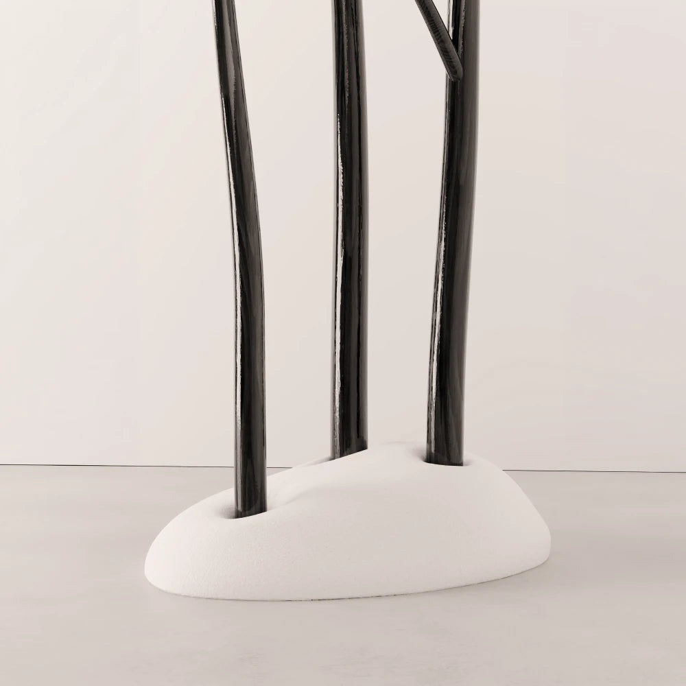 Lower view of Antony Gasnier’s Winter Tree Coats Triple, with three dark wood trunks set into a rounded white upholstered base.