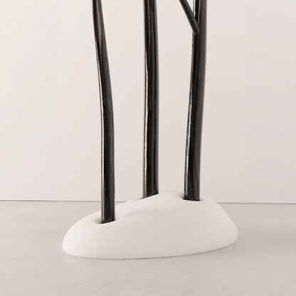 Lower view of Antony Gasnier’s Winter Tree Coats Triple, with three dark wood trunks set into a rounded white upholstered base.