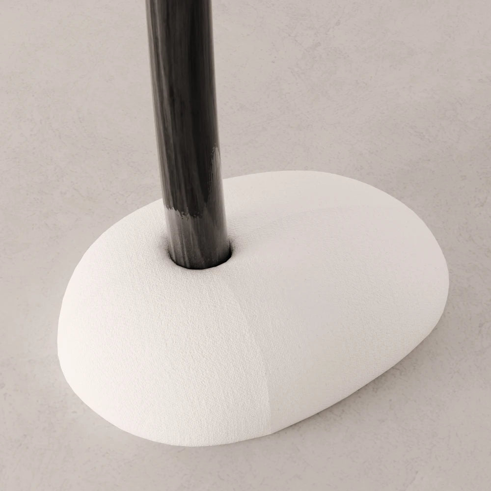 Close-up of the rounded white upholstered base and dark wood trunk of the Winter Tree coat stand by Antony Gasnier