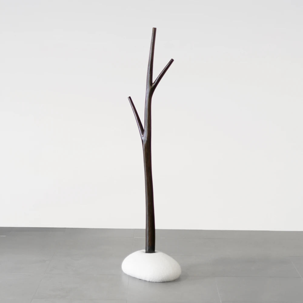 Full view of the Winter Tree coat stand in dark wood with a white upholstered base by Antony Gasnier