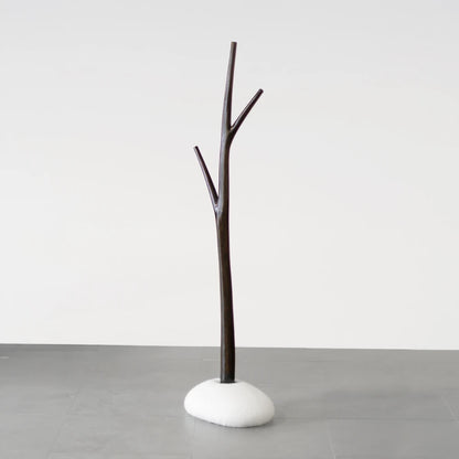 Full view of the Winter Tree coat stand in dark wood with a white upholstered base by Antony Gasnier