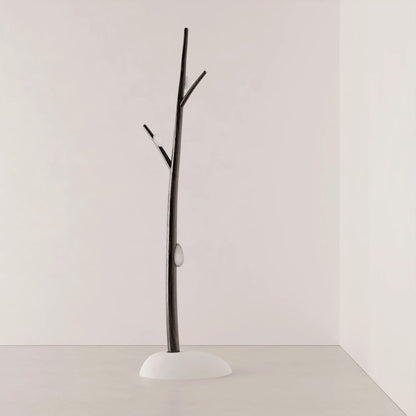 Full view of Antony Gasnier’s Winter Tree Light floor lamp, with a dark wood trunk, branch-like arms and white upholstered base.