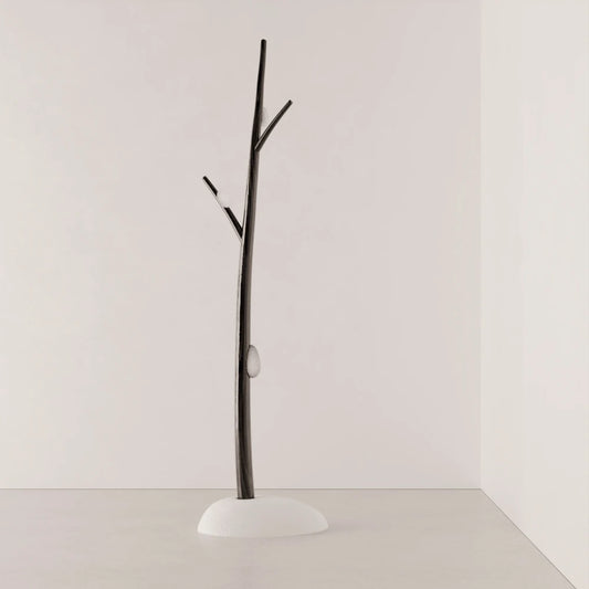 Full view of Antony Gasnier’s Winter Tree Light floor lamp, with a dark wood trunk, branch-like arms and white upholstered base.