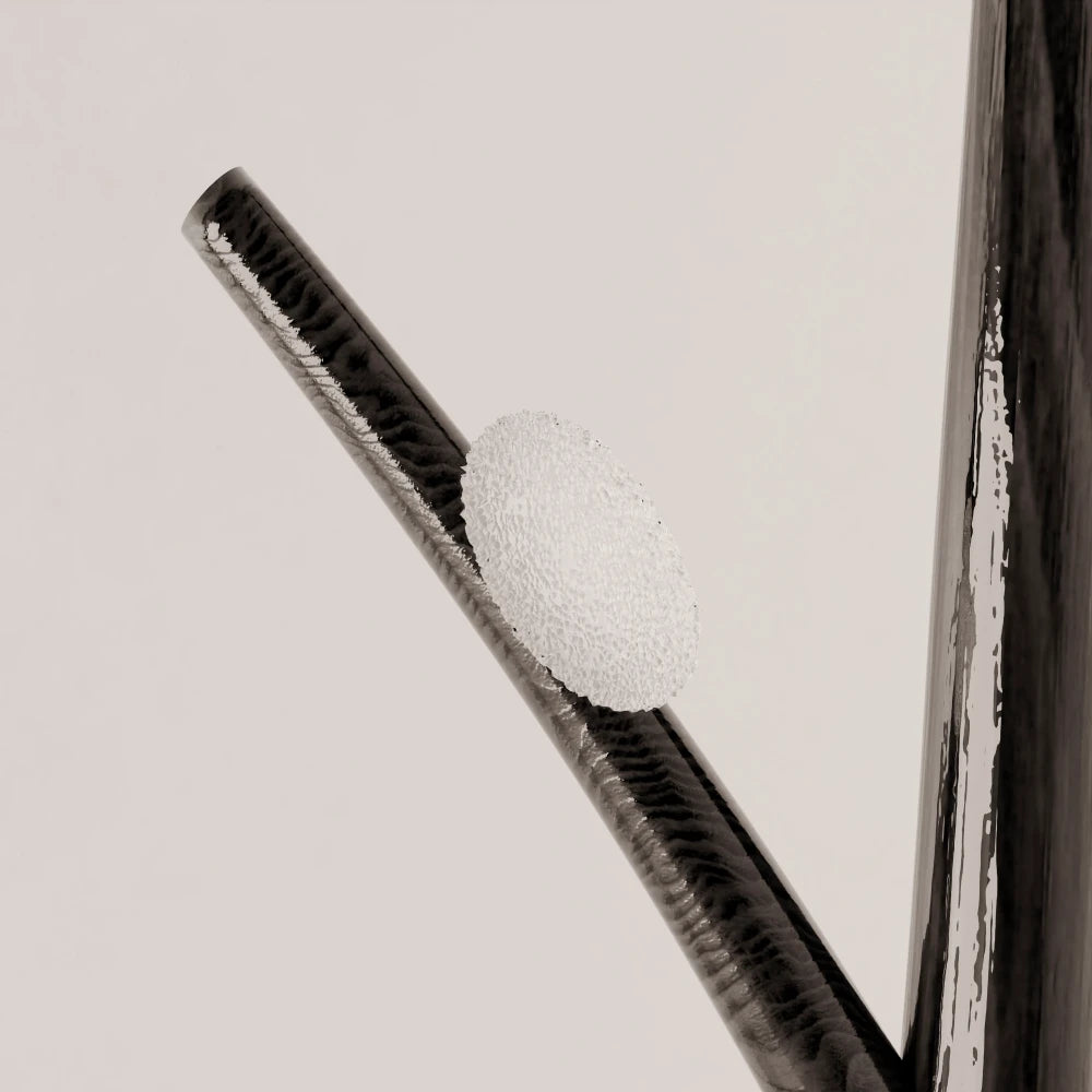 Close-up of a textured glass diffuser mounted on the dark wood branch of Antony Gasnier’s Winter Tree Light floor lamp.