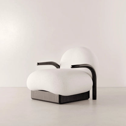Winter Armchair in solid oak and white fabric by Antony Gasnier, three-quarter view showing its curved armrests and generous seat