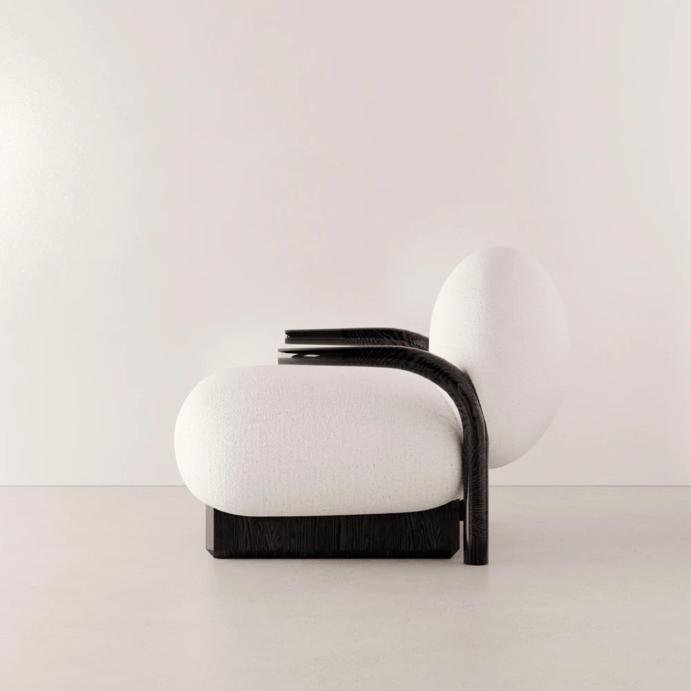 Side view of the Winter Armchair by Antony Gasnier, highlighting the dark oak armrest extending from the backrest to the floor