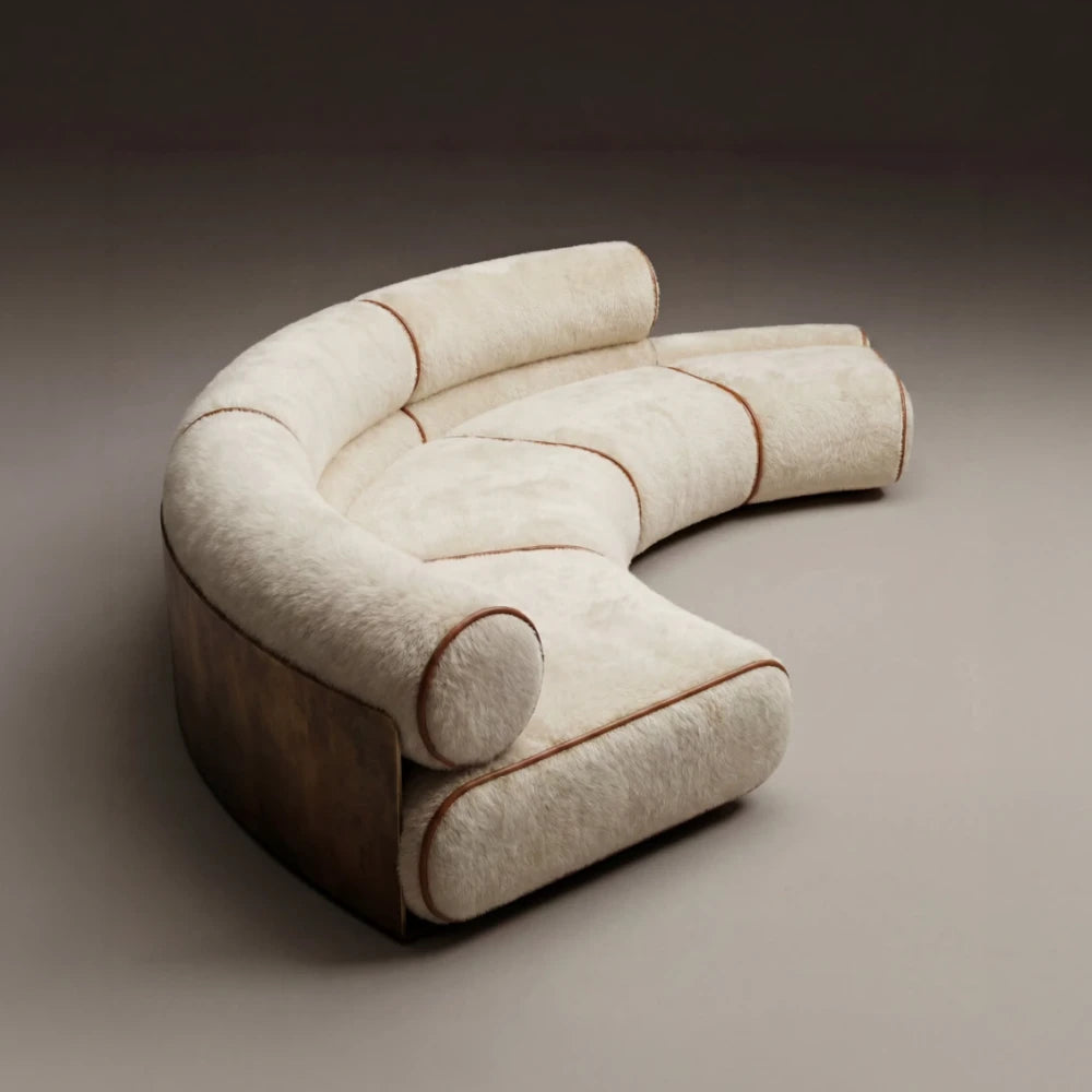 High-angle view of the curved Étreinte sofa, with modular cream seats, cylindrical backrests and contrasting brown piping.