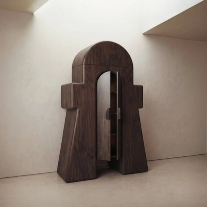 Three-quarter view of the Le Gardien cabinet by Diamant Versatile, with its arched dark wood doors partially open.